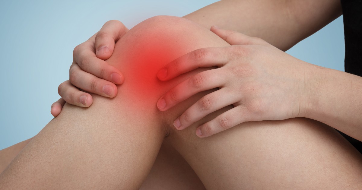 person sitting holding their knee with pain indicators around the knee